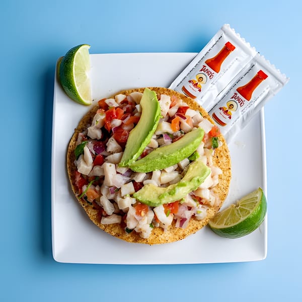 Baja California Tacos' ceviche tostada with avocado, lime, and Tapatío hot sauce packets.